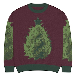Op de afbeelding: Bordeauxkleurige trui met ronde hals en een groen kerstboomontwerp. De boom is bekroond met een groene ster. De mouwen en de halslijn zijn groen afgewerkt.
