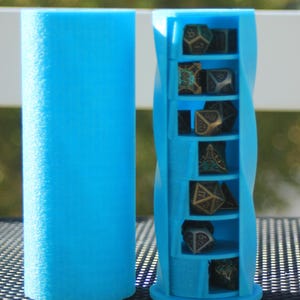 May include: A light blue, 3D-printed dice tower and storage container. The tower has a spiral design with six compartments holding various polyhedral dice. A separate cylindrical piece is also visible.
