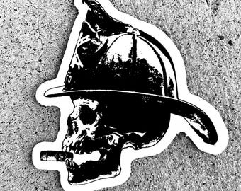 May include: Black and white sticker of a skull wearing a firefighter's helmet. The skull is smoking a cigarette.