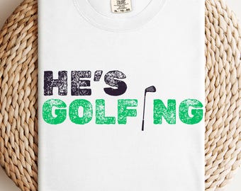 Comfort Colors® He's Golfing Shirt, Golfing Season Shirt, Golfer Wife Shirt, Golfing Mom Shirt, Golf Player Shirt for Mom, Golf Lover Shirt