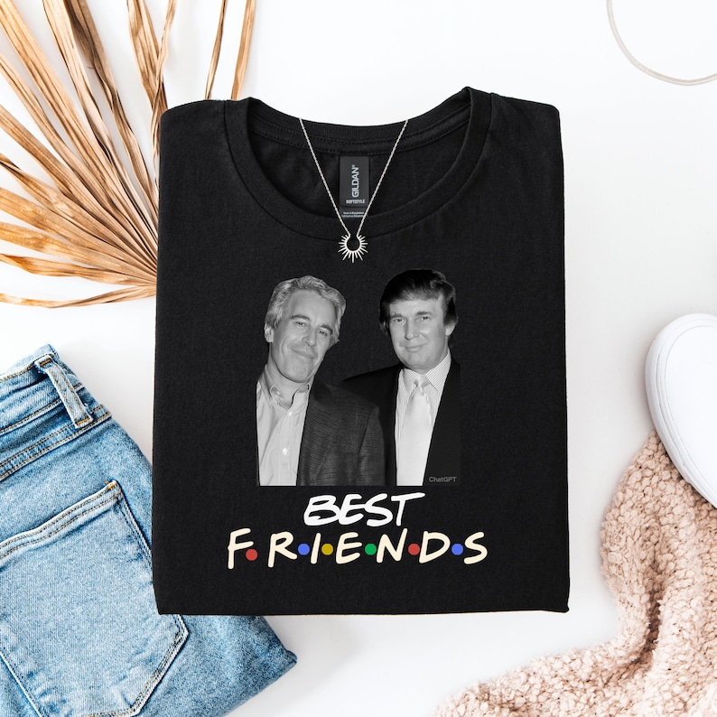 May include: Black t-shirt with a black and white image of two men. The text "BEST FRIENDS" is printed in colourful letters below the image. A silver necklace with a sun pendant is on the shirt.