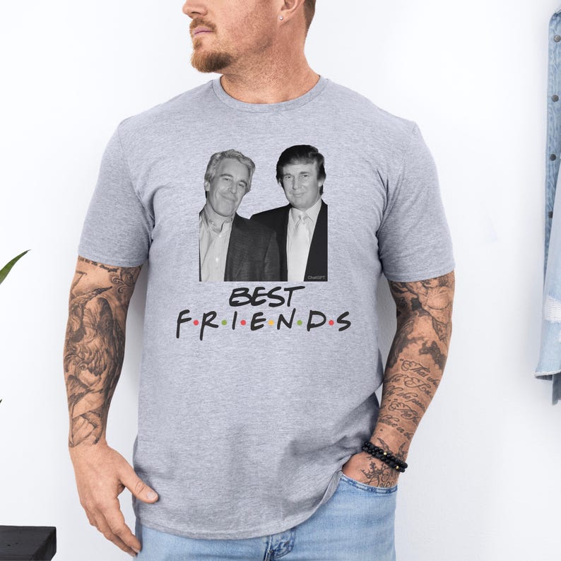 May include: A light grey t-shirt with a graphic of two men in suits and the text "BEST FRIENDS" in colourful letters. The shirt has a crew neck.