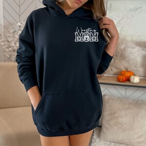 May include: Black hooded sweatshirt with a white graphic that says "Wrestling Mom" in a sporty font.