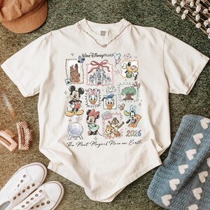 Puede incluir: Camiseta color crema con un gr&aacute;fico colorido de personajes y lugares emblem&aacute;ticos de Disney. El dise&ntilde;o incluye a Mickey Mouse, Minnie Mouse, Donald Duck y un castillo. Tambi&eacute;n se ve el texto "Walt Disney World" y "The Most Magical Place on Earth".