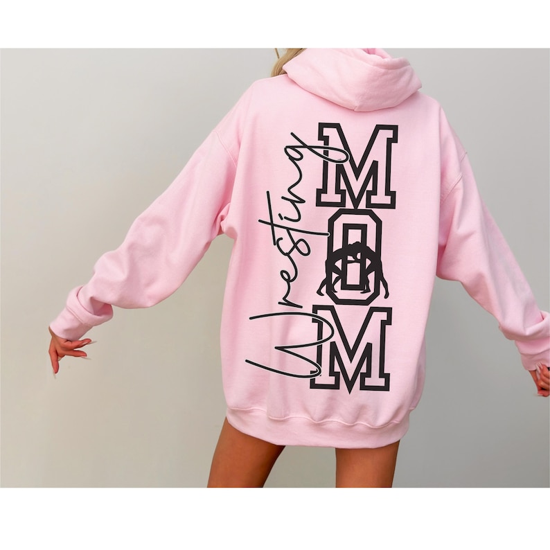 May include: Pink hooded sweatshirt with the text "Wrestling Mom" in black lettering on the back.