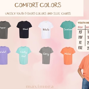 Puede incluir: Una exhibici&oacute;n de camisetas Comfort Colors para j&oacute;venes en varios colores, incluyendo negro, blanco y violeta. La imagen incluye una tabla de tallas con medidas en cm para tallas juveniles YS a YXL. El texto "COMFORT COLORS" est&aacute; en la parte superior.