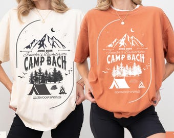 May include: Two t-shirts, one ivory and one yam-colored, featuring a mountain and camping-themed graphic. The design includes text that reads "June 2025 Jennifer's Bachelorette Camp Bach" and "Glenwood Springs."