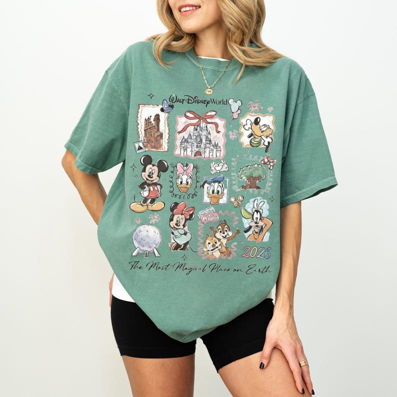 Puede incluir: Camiseta verde con un gr&aacute;fico de Disney World con Mickey Mouse, Minnie Mouse, Donald Duck y otros personajes. La camiseta tiene el texto "The Most Magical Place on Earth" y el a&ntilde;o "2026".