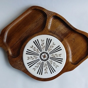 Op de afbeelding: Een houten dienblad met drie compartimenten. Het middelste compartiment heeft een witte keramische inzet met een zwart en gouden bloemenontwerp.