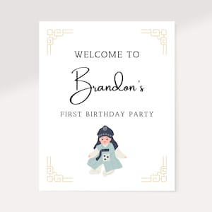 Peut inclure: Une pancarte d'accueil blanche avec des bordures dorées et le texte "Bienvenue à la fête du premier anniversaire de Brandon". Une illustration de dessin animé d'un garçon portant une tenue traditionnelle coréenne se trouve au centre de la pancarte.