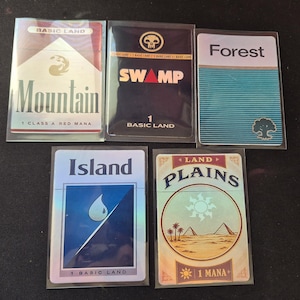 May include: Five rectangular trading cards in clear protective sleeves. The cards feature stylized designs for Mountain, Swamp, Forest, Island, and Plains, each labeled with its name, basic land status, and mana-related text and symbols.