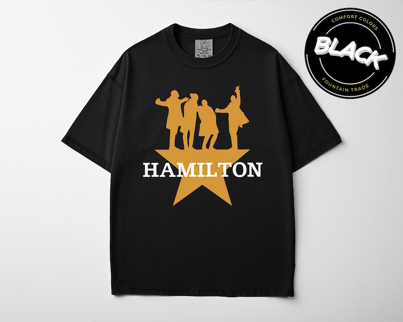 A black t-shirt with a graphic design featuring silhouettes of three people and a star, along with the text "HAMILTON" printed on it.