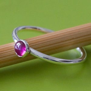May include: A silver ring with a pink gemstone set in the center.