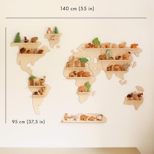 May include: A wooden world map shelf, 140 cm wide and 95 cm high, with wooden animal figurines. The shelves are shaped like continents and are mounted on a white wall. The animals are in various colors and shapes.