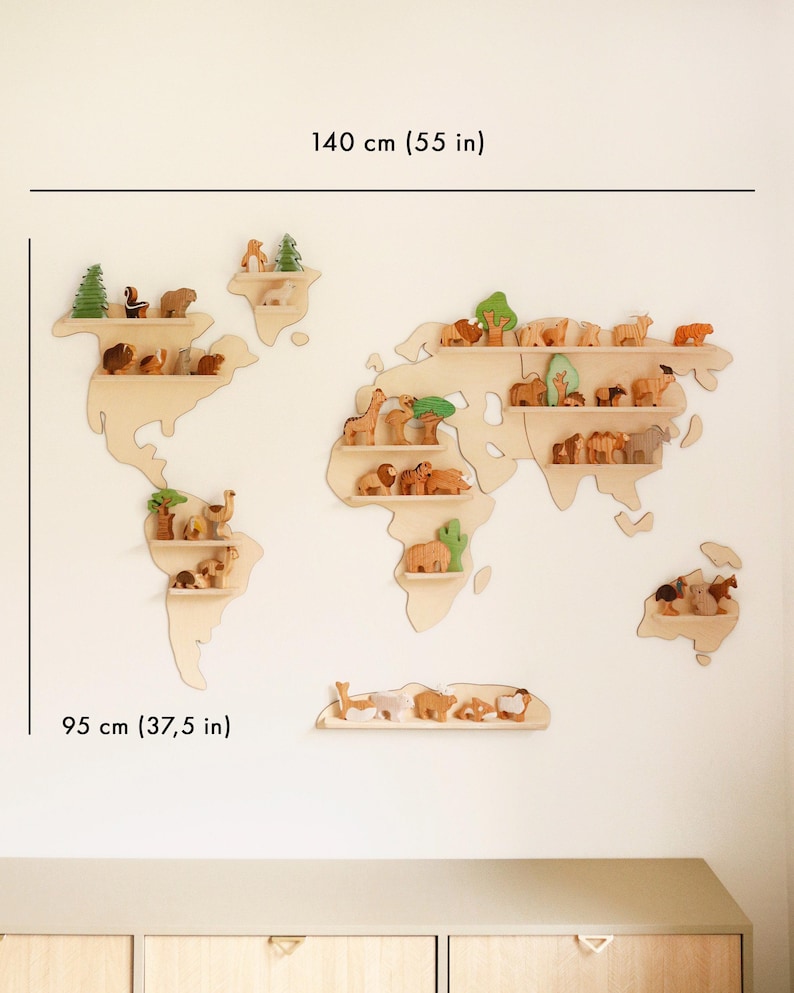 May include: A wooden world map shelf, 140 cm wide and 95 cm high, with wooden animal figurines. The shelves are shaped like continents and are mounted on a white wall. The animals are in various colors and shapes.