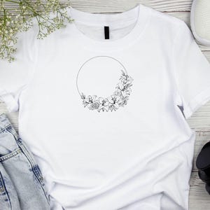 Puede incluir: Camiseta blanca con un contorno negro de un c&iacute;rculo con flores alrededor.