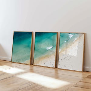 Peut inclure: Trois impressions encadrées d'une vue aérienne d'une plage avec de l'eau turquoise et du sable blanc. La plage est bondée de monde.