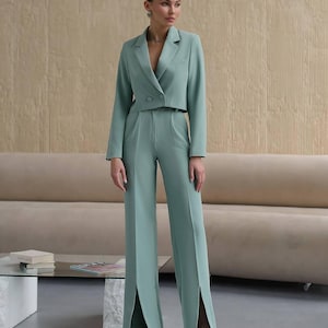 K&ouml;nnte beinhalten: Ein mintgr&uuml;ner Hosenanzug mit einer kurzen Jacke und einer weiten Hose mit Schlitzen am Saum.