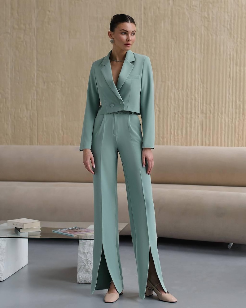 K&ouml;nnte beinhalten: Ein mintgr&uuml;ner Hosenanzug mit einer kurzen Jacke und einer weiten Hose mit Schlitzen am Saum.
