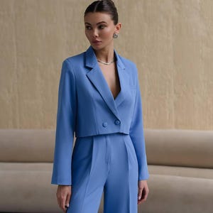 K&ouml;nnte beinhalten: Ein blauer, kurzer Blazer mit doppelreihigem Verschluss und langen &Auml;rmeln. Der Blazer wird mit einer passenden weiten Hose kombiniert.