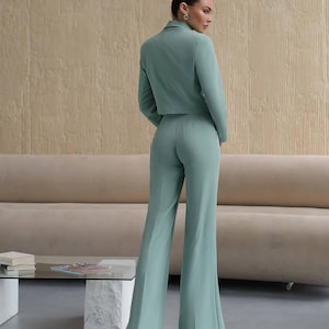 K&ouml;nnte beinhalten: Ein hellgr&uuml;ner, kurzer Blazer und eine passende weite Hose. Der Blazer hat einen zweireihigen Verschluss und einen Schalkragen.