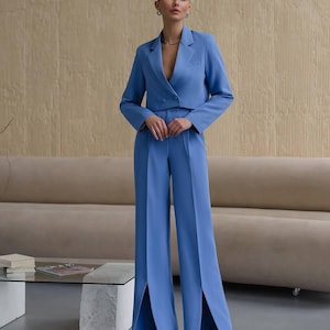 K&ouml;nnte beinhalten: Ein blauer, kurzer Blazer und eine passende, weite Hose mit Schlitzen am Saum. Die Hose hat eine hohe Taille und eine schmale Passform.