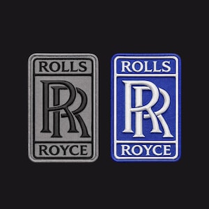 May include: Two embroidered Rolls-Royce patches. One has a grey background with black text and logo, the other a blue background with white text and logo. The patches are rectangular with rounded corners, suitable for application on clothing or accessories.