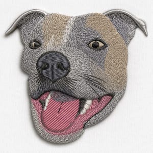 Puede incluir: Un parche bordado que muestra la cabeza de un perro con pelaje gris y beige. El perro tiene una nariz gris oscuro, dientes blancos visibles y una lengua rosa colgando. El bordado utiliza puntadas detalladas para crear textura y profundidad.