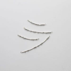 May include: Four silver-colored, curved jewelry components. Each component features a series of small, round beads strung along a thin, straight bar. The ends of each bar have small loops, suggesting they are designed for connecting to other jewelry pieces.
