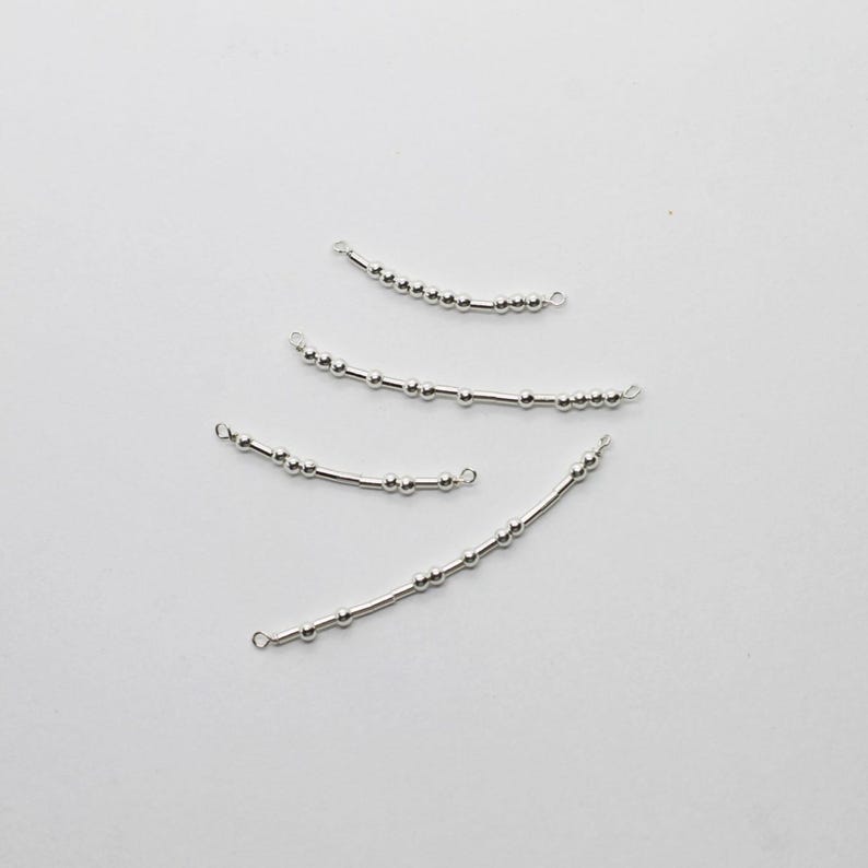 May include: Four silver-colored, curved jewelry components. Each component features a series of small, round beads strung along a thin, straight bar. The ends of each bar have small loops, suggesting they are designed for connecting to other jewelry pieces.