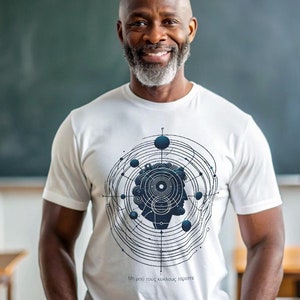 Może przedstawiać: Biały t-shirt z geometrycznym wzorem przedstawiającym sylwetkę ludzkiej głowy. Wzór zawiera koła, linie i kropki. Na koszulce nadrukowany jest tekst "Μή μου τους κύκλους τάραττε".