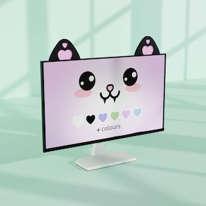 Puede incluir: Un monitor de computadora con un diseño temático de gato. La pantalla muestra una cara de gato rosa con ojos negros, mejillas rosas y una nariz negra. El monitor tiene orejas de gato negras en la parte superior. La pantalla también muestra corazones y el texto "+ colores".