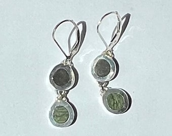 May include: A pair of silver dangle earrings with two round green and black stones on each earring.