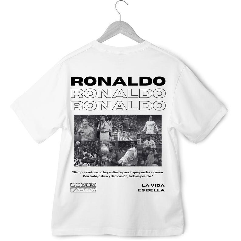 May include: White t-shirt with a black and white photo collage of a soccer player. The text "RONALDO" is repeated three times in a stacked format. The quote "Siempre crei que no hay un limite para lo que puedes alcanzar. Con trabajo duro y dedicaci&oacute;n, todo es posible." is printed below the collage. The text "LA VIDA ES BELLA" is printed below the quote.