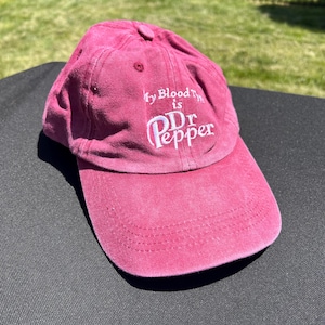 Puede incluir: Una gorra de béisbol rosa con el texto "My Blood Type is Dr Pepper" bordado en la parte delantera.