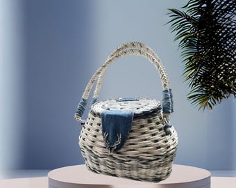 May include: A white and blue woven basket with a denim flap and a deer head accent. The basket has two handles and is sitting on a white pedestal.