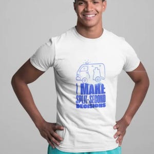 May include: White t-shirt with a blue ambulance graphic and the text "I MAKE SPLIT-SECOND DECISIONS". The person is wearing turquoise scrubs. The image is a medium shot.