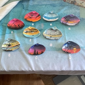 May include: Nine painted seashells with various sunset and beach scenes. Each seashell is numbered 1 through 9.