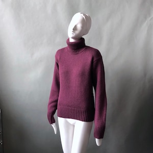 May include: A deep burgundy turtleneck sweater with a ribbed knit texture.