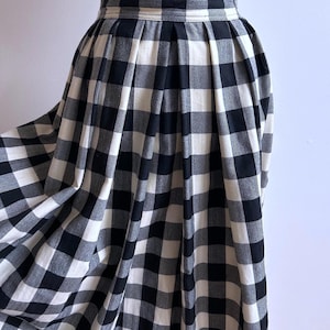 May include: A black and white checkered skirt with a high waist and pleated design. The skirt is made of a soft fabric and has a full, flowing silhouette. The classic gingham pattern is a timeless style.