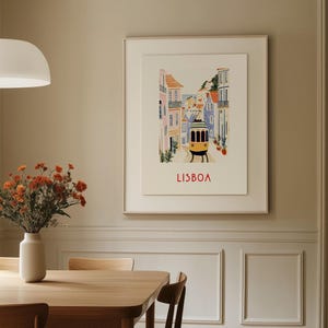 May include: A framed illustration of a street scene in Lisbon, Portugal. The illustration features colorful buildings, a yellow tram, and the word "LISBOA" in red lettering.