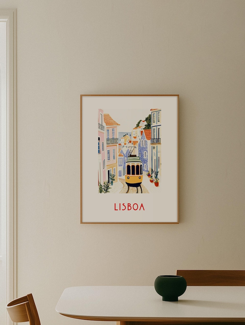 May include: A framed illustration of a yellow tram traveling through a narrow street in Lisbon, Portugal. The buildings are colorful and have tiled facades. The text "LISBOA" is printed in red at the bottom of the illustration.