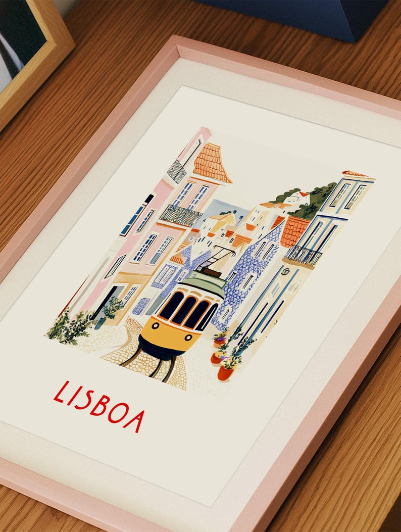 May include: A framed illustration of a yellow tram traveling through a colorful, narrow street in Lisbon, Portugal. The illustration features buildings with tiled facades and lush greenery. The word "LISBOA" is written in red at the bottom of the illustration.