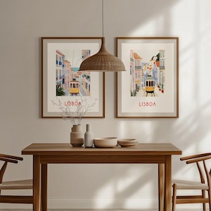 May include: Two framed vintage travel posters with illustrations of Lisbon, Portugal. The posters feature a yellow tram traveling up a hill with colorful buildings on either side. The text "LISBOA" is printed in red at the bottom of each poster.