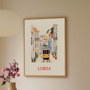 May include: A vintage-style illustration of a yellow tram traveling through a colorful street in Lisbon, Portugal. The buildings are painted in shades of pink, blue, and yellow, and the street is lined with potted plants. The text "LISBOA" is printed in red at the bottom of the image.