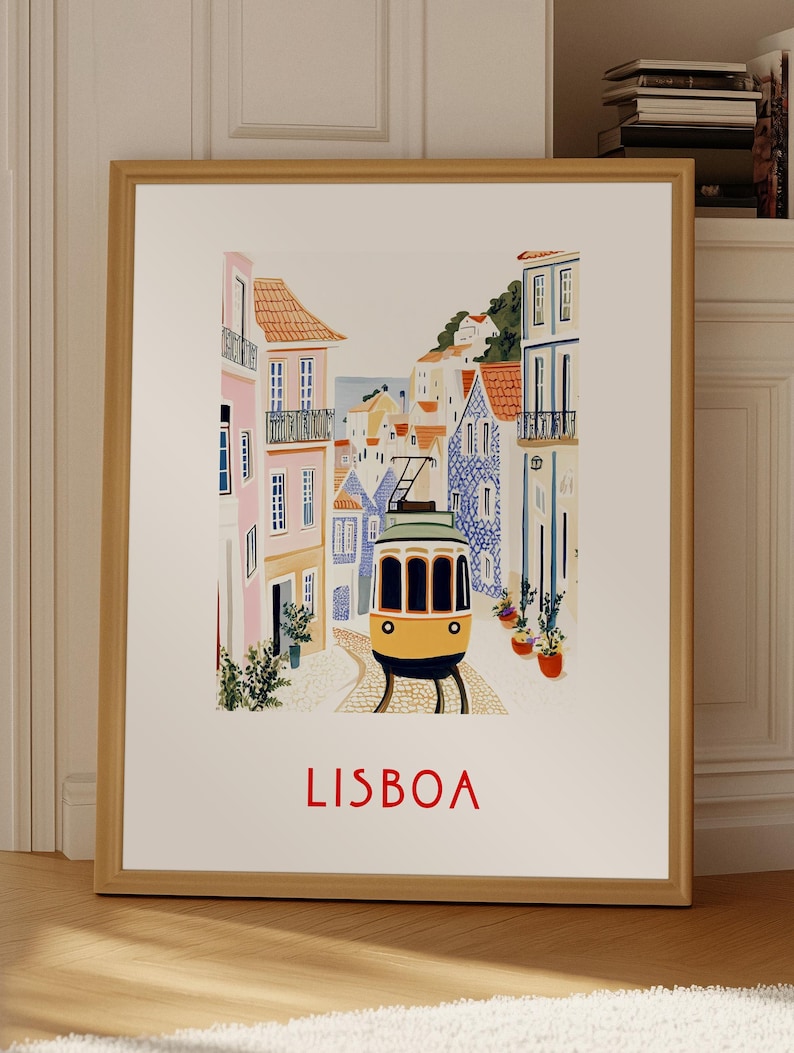 May include: A framed print of a colorful illustration of a yellow tram traveling through a street in Lisbon, Portugal. The buildings are painted in shades of pink, blue, and white. The text "LISBOA" is printed in red at the bottom of the print.