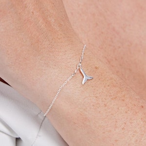 Può includere: Un braccialetto a catena d'argento con un piccolo ciondolo a forma di coda di sirena d'argento.
