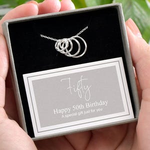 May include: A silver necklace with five interlocking circles in a gift box with a card that reads "Fifty Happy 50th Birthday A special gift just for you".