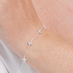 May include: A silver chain bracelet with small star-shaped charms set with clear cubic zirconia stones.
