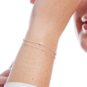 Puede incluir: Un brazalete de plata con peque&ntilde;as piedras redondas. El brazalete se lleva en la mu&ntilde;eca.